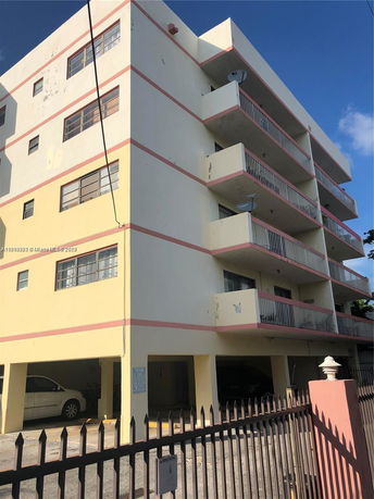 Front view of a multi-story apartment building with balconies and a gated entrance.