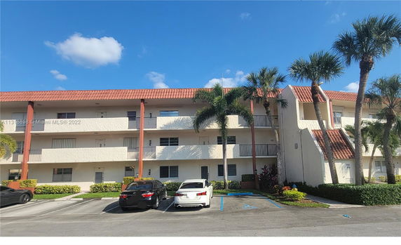 Front view of a three-story residential building with balconies and a red-tiled roof.