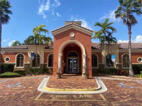 Front view of a building with a central arched entrance and surrounding windows.