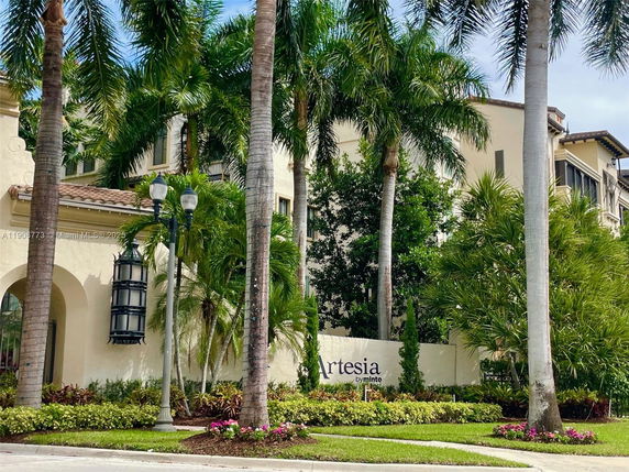 Front view of a multi-story residential building with palm trees and a sign reading 'Artesia'.