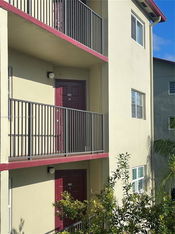 View of a multi-story building with balconies and red doors.