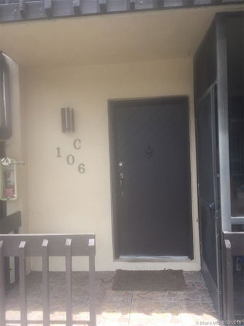 Front view of a building entrance with a dark door and tiled flooring.