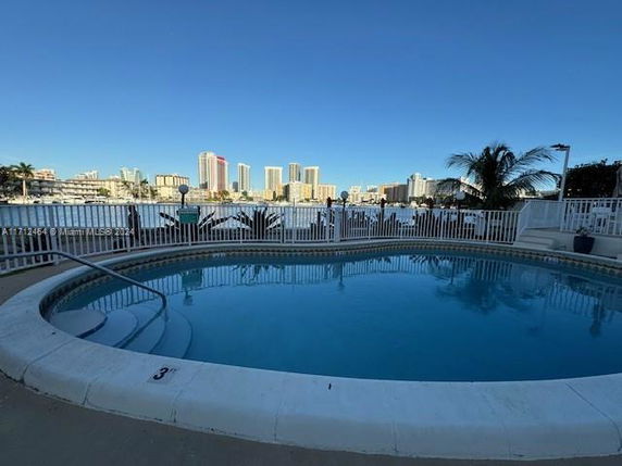 Outdoor swimming pool with a view of cityscape buildings in the background.