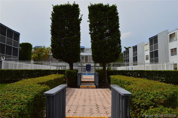 Front view of a multi-story residential building with screened balconies and a gated entrance.