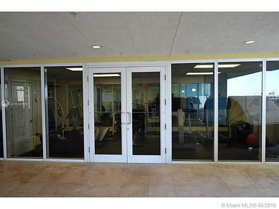 Glass entrance to an indoor gym with exercise equipment visible inside.