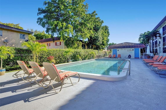 Outdoor swimming pool with lounge chairs and surrounding greenery.