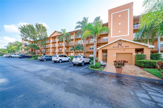 Front view of a multi-story residential building with parking area.