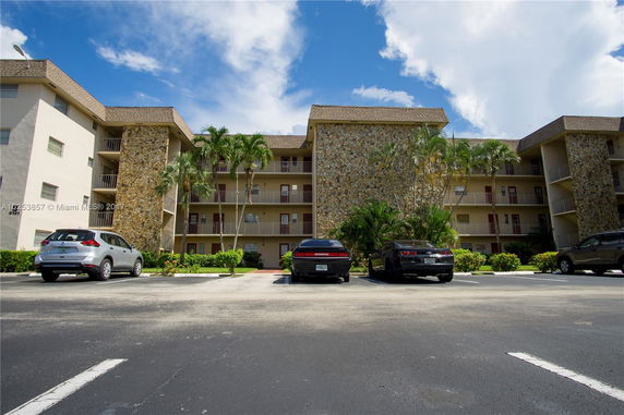 Front view of a multi-story residential building with stone exterior details and balconies.