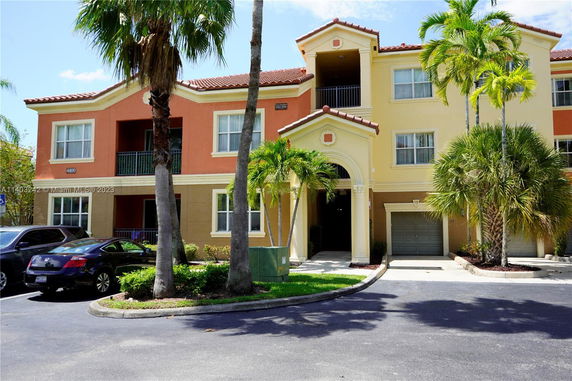 Front view of a two-story building with a garage and palm trees.