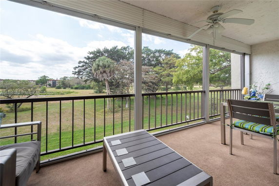 Panoramic view from a balcony showing a grassy area and trees.
