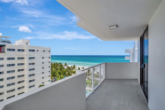 Balcony view overlooking the ocean and adjacent buildings.