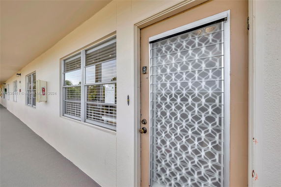 Corridor view of an apartment building with a patterned glass door and windows.