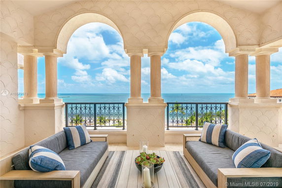 Outdoor seating area with arched columns and a view of the ocean.