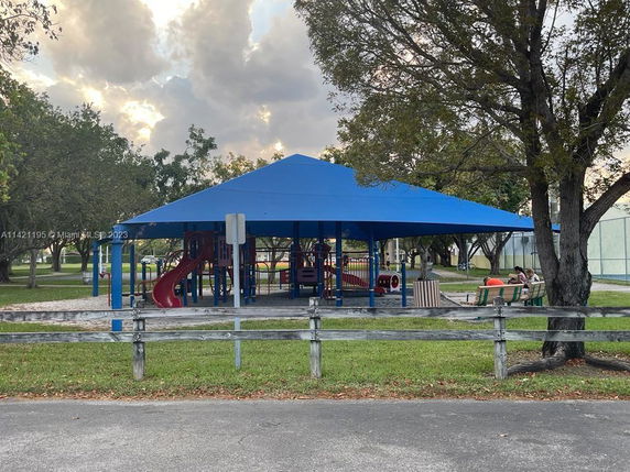 Outdoor play area with a blue canopy cover and playground equipment.