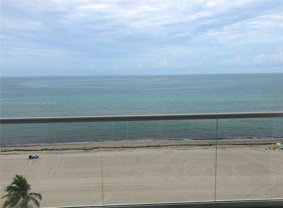 Panoramic view of a beach and ocean from a balcony.