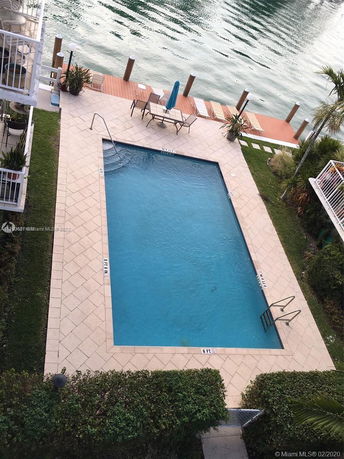Aerial view of a rectangular swimming pool adjacent to a waterfront dock.