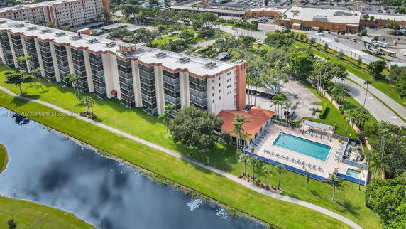 Aerial view of a multi-story residential building with a swimming pool and landscaped areas.