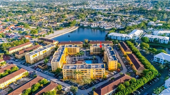 Aerial view of a large apartment complex with surrounding residential area and a water body.