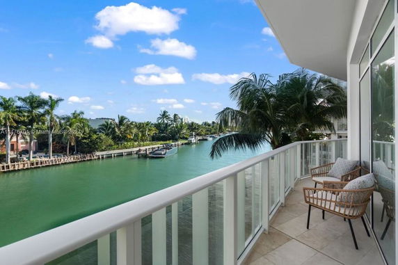 View from a balcony overlooking a waterway with palm trees and boats.