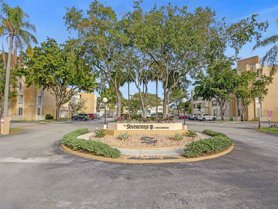 Front view of a residential condominium complex with multiple buildings and parking area.