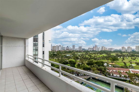Balcony view overlooking a golf course and city skyline in the distance.
