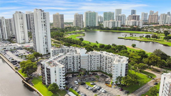 Aerial view of a high-rise residential complex with surrounding greenery and water bodies.