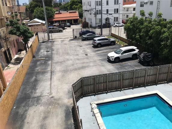 Outdoor parking area with multiple cars parked and a swimming pool nearby.