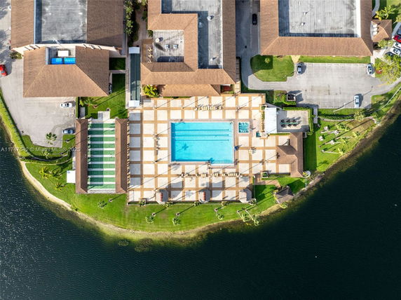 Aerial view of a complex featuring a swimming pool and surrounding buildings near a body of water.