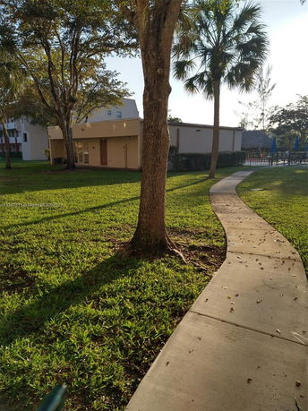 View of a small building surrounded by trees and a pathway.