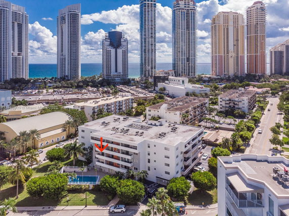 Aerial view of a beachfront urban area with multiple high-rise buildings and a nearby swimming pool.