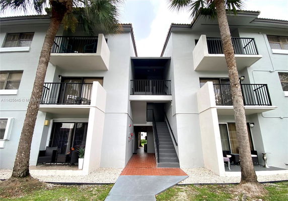 Front view of a two-story building with balconies and an entrance staircase.