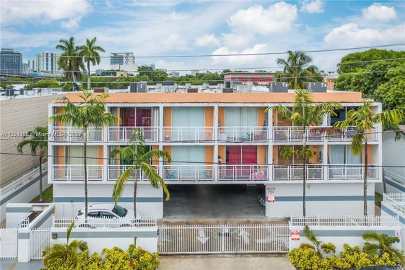 Front view of a three-story apartment building with balconies and a gated entrance.