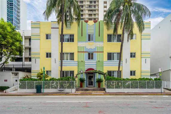 Front view of a multicolored building with palm trees.