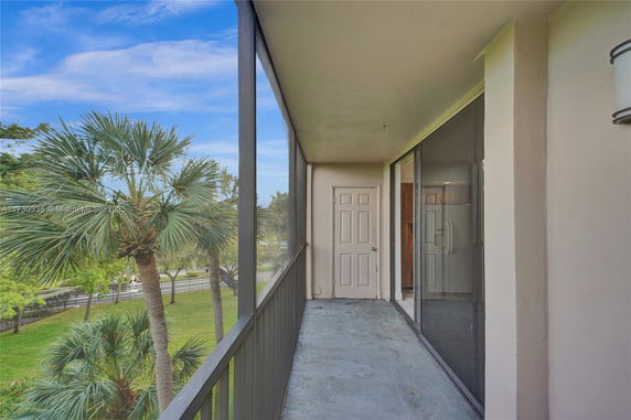 View from a balcony overlooking palm trees and a grassy area.
