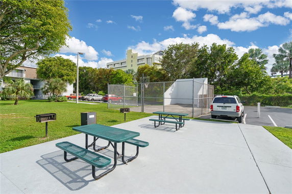 Outdoor play area with a basketball court and picnic tables.