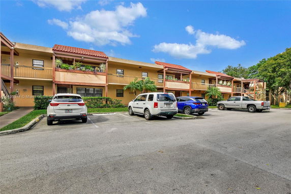 Front view of a two-story apartment building with parked cars in front.