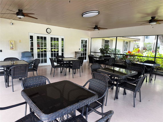 Covered outdoor seating area with tables and chairs in a clubhouse setting.