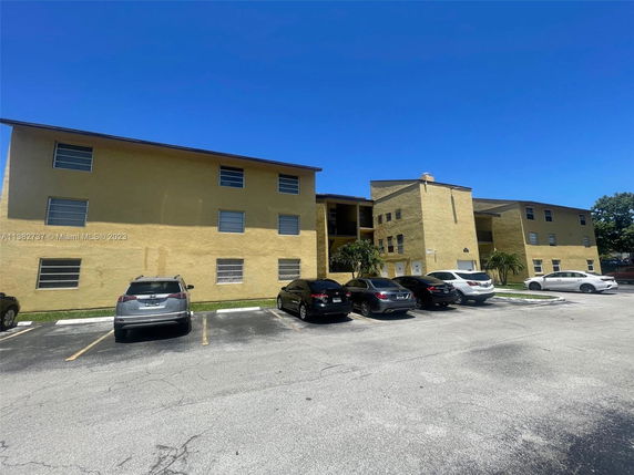 Front view of a three-story apartment building with parking area.