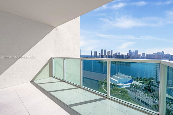 Panoramic view of a waterfront cityscape from a high-rise balcony.