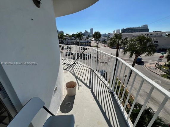 Outdoor view from a balcony overlooking a street and buildings.