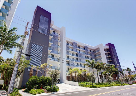 Front view of a multi-story modern apartment building with balconies.