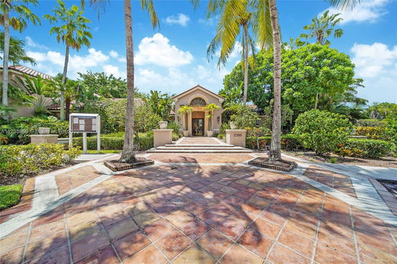 Front view of a house with a tiled walkway and tropical landscaping.