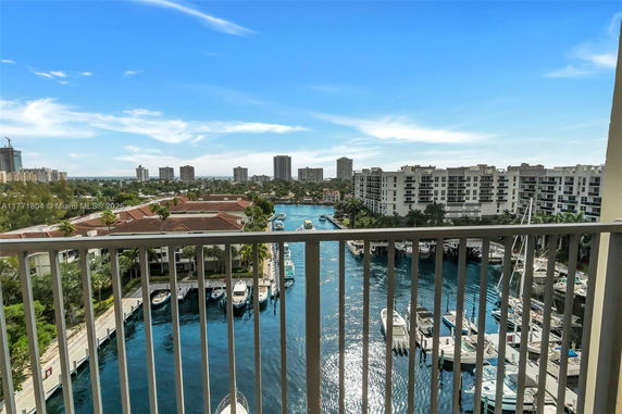 View from a balcony overlooking a waterway with boats and nearby buildings.