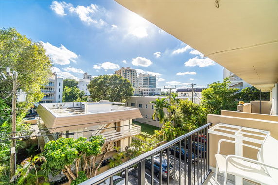 View from a balcony showing nearby buildings and trees.