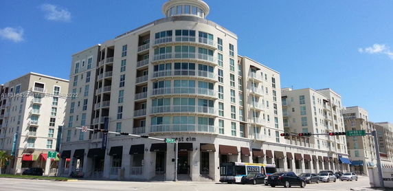 Front view of a multi-story residential and commercial building with large windows and balconies.