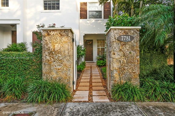 Front view of a two-story house with a stone walkway and entrance gate.