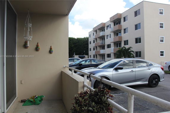 Exterior view of apartment building with adjacent parking area.
