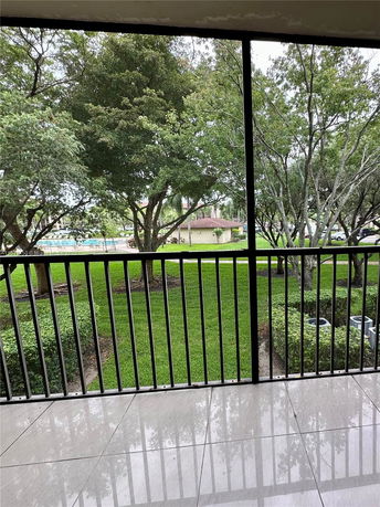 View from a balcony showing trees, a lawn, and a building in the background.