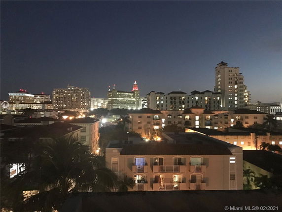 Panoramic view of city buildings at night with illuminated windows.