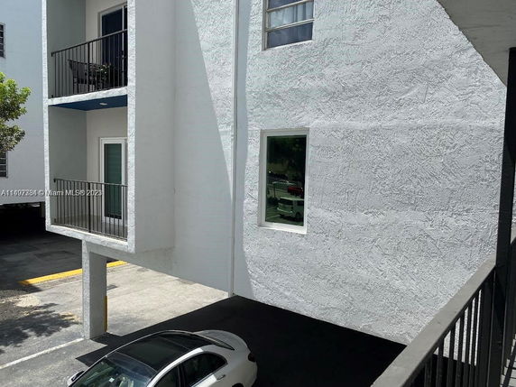 Parking area beneath a white building with balconies.